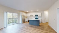 Located at 160 Ash Street East in Annandale, MN, this well-appointed single-floor unit offers three bedrooms, two bathrooms, and a thoughtfully designed layout. The open-concept living, dining, and kitchen area serves as the heart of the home, featuring light wood-style luxury vinyl plank flooring, recessed lighting, and a sliding glass door that opens to a private balcony with outdoor views. The kitchen is outfitted with crisp white shaker cabinets, white quartz countertops, a two-tone island with slate-blue cabinetry, and a full suite of stainless steel appliances including a refrigerator, range, microwave, and dishwasher. A central hallway connects the bedrooms, which feature plush carpeting and natural light from well-placed windows. The primary bedroom offers a generous footprint with its own dedicated bathroom, complete with a walk-in shower, white vanity with quartz countertops, and ample built-in storage. A second full bathroom serves the remaining bedrooms. Six closets throughout the unit provide abundant storage, and a dedicated laundry area adds everyday convenience. The clean, neutral palette and modern finishes give the entire space a fresh, move-in-ready feel.