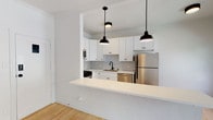Located on Hyperion Avenue in the heart of Silver Lake, Los Angeles, this single-floor unit showcases a clean, modern aesthetic with consistent design choices throughout. Light hardwood flooring runs continuously across the open-plan living and kitchen areas, creating a cohesive and airy feel.

The kitchen is a standout feature, designed with crisp white shaker cabinetry, a geometric hexagonal tile backsplash, and a full suite of stainless steel appliances including a gas range, dishwasher, microwave, and refrigerator. A black matte faucet adds a contemporary contrast, while a peninsula with a white countertop extends into the living area, providing additional prep space and an informal dining option. Three industrial-style black pendant lights illuminate the kitchen zone.

The adjoining living area is bright and open, benefiting from multiple windows that invite natural light. A ceiling fan with a built-in light fixture adds comfort and function to the space.

The bathroom continues the black-and-white theme with a classic penny tile floor, white subway-tiled tub surround, a white vanity with black hardware, and a recessed medicine cabinet. The result is a cohesive, timeless aesthetic that complements the overall modern sensibility of the unit.