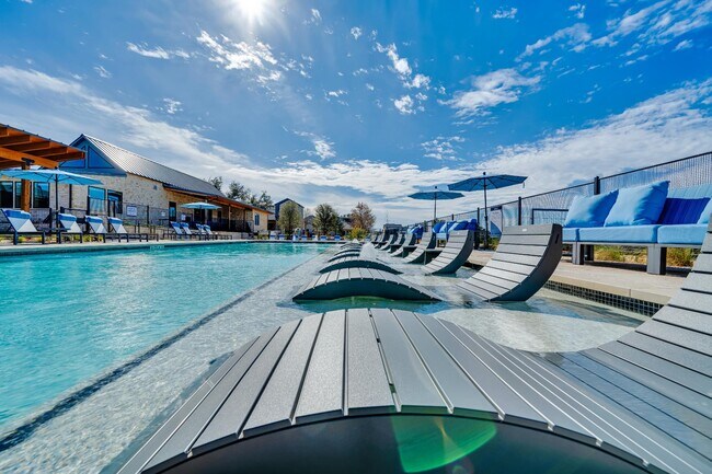 Un día soleado en la piscina al aire libre, con agua azul y tumbonas. - parcHAUS at Mustang Drive