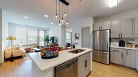 Located at 555 Dresher Rd in Horsham, Pennsylvania, this single-floor residence offers a thoughtfully designed open-concept layout with modern finishes throughout. The kitchen is a standout feature, showcasing gray shaker-style cabinetry, white quartz countertops, a full suite of stainless steel appliances including a gas range, microwave, refrigerator, and dishwasher, and a central island with a built-in sink and pendant globe lighting above. Light hardwood flooring flows seamlessly through the kitchen and living areas, creating a bright, cohesive aesthetic. The living area is bathed in natural light through large windows and a glass door that opens to a private balcony with outdoor views. Multiple bedrooms provide comfortable retreats, each featuring plush carpeting, generous windows, and ample natural light. The primary bedroom benefits from a wide window bank and an elegant multi-globe light fixture. Bathrooms are finished with large-format marble-style tile flooring and gray vanity cabinetry with white countertops, and include walk-in closet access. The overall ambiance is clean, contemporary, and inviting, combining functional design with modern materials throughout every room.