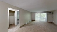Located at 508 Ivy Ridge Rd in Syracuse, NY, this single-floor residence offers a well-organized layout with two bedrooms, two bathrooms, a kitchen, a living room, and four closets providing generous storage throughout. The living room is a standout space, featuring plush wall-to-wall carpeting, a baseboard heating system, and a large sliding glass door with vertical blinds that frames lush greenery and invites abundant natural light. A closet with built-in shelving is conveniently accessible from this area. The kitchen is equipped with dark wood cabinetry, stone-finish countertops, a double-basin sink, a dishwasher, and tile flooring, complemented by a window with outdoor views. The primary bedroom is a comfortable retreat with carpet flooring, a sliding closet, a baseboard heater, and a window overlooking the surrounding landscape. The second bedroom is equally well-appointed with carpet and neutral tones. Both bathrooms feature tile flooring, and at least one includes a full bathtub and shower combination with a vanity and stone-finish countertop. The warm, neutral color palette and practical finishes throughout create a clean and functional living environment.