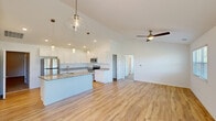Located at 8495 Hoke Rd in Clayton, Ohio, this single-story home showcases a thoughtfully designed open-concept layout that seamlessly connects the kitchen and living areas. The kitchen is a standout feature, boasting white shaker-style cabinetry extending to the ceiling, speckled granite countertops, a central island with pendant lighting, and a full suite of stainless steel appliances including a refrigerator, range, and microwave. Recessed lighting and vaulted ceilings enhance the sense of openness throughout this space.

Light-toned hardwood flooring flows through the main living areas, complemented by ceiling fans that add both function and style. The living area benefits from multiple windows fitted with blinds, allowing generous natural light and outdoor views. Bedrooms feature plush carpeting and tray ceilings with ceiling fans, adding architectural detail and comfort. Natural light filters in through well-placed windows in each bedroom.

The bathroom is clean and functional, featuring a wide vanity with a white countertop, a large mirror, and hardwood-style flooring. A spacious walk-in closet with wire shelving and carpeted flooring provides ample storage. Overall, the home presents a bright, modern, and well-appointed interior throughout.