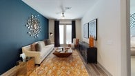 This two-bedroom, two-bathroom residence is thoughtfully designed across a single floor, combining contemporary finishes with functional living spaces. The living room serves as a striking centerpiece, featuring wood-look flooring, a ceiling fan, and French doors that invite natural light. A bold teal accent wall and decorative touches give the space a distinct, modern character.

The kitchen is outfitted with light wood-grain cabinetry, a textured tile backsplash, quartz countertops, and a full suite of stainless steel appliances, including a French door refrigerator, range, microwave, and dishwasher. A kitchen island provides additional prep and dining space.

Both bedrooms are carpeted and comfortably sized, each with a ceiling fan. The primary bedroom features a geometric accent wall and a large window, while the second bedroom is served by a walk-in closet with multi-level shelving. Each bathroom includes wood-look flooring, a single-sink vanity with quartz countertops, and a tub-shower combination. One bathroom features an elongated layout with generous counter space, while the other is appointed with clean white tilework and modern fixtures.
