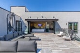Located at 72 Milton Ave SE in Atlanta, GA, this contemporary single-floor space offers a sophisticated blend of modern design and functional amenities. The interior is defined by soaring vaulted ceilings that amplify the sense of openness throughout, while large, floor-to-ceiling windows flood every area with abundant natural light and frame sweeping views of the surrounding Atlanta skyline and treetops.

The main living and lounge area features sleek tile flooring, curated artwork, and a striking textured gold accent wall that anchors the room with bold visual interest. A stylish globe chandelier adds a touch of contemporary elegance to the game area, which includes a full-size pool table and comfortable seating arrangements with leather accent chairs. Adjacent to the lounge, a dedicated dining area accommodates large gatherings around a substantial wooden table beneath a mid-century modern chandelier, complemented by a long built-in counter along a wall of vertical lighting sconces.

The space seamlessly connects to a generous outdoor deck through expansive folding glass doors, creating an effortless indoor-outdoor flow. The deck features natural wood decking, ample lounge seating, and a retractable umbrella, making it ideal for entertaining. Throughout the space, the neutral palette, modern furnishings, and panoramic views combine to create a polished, welcoming atmosphere.