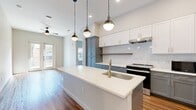 This contemporary 1010-square-foot apartment in Austin, TX, offers a harmonious blend of style and functionality. The space boasts two bedrooms and two bathrooms, with the primary bedroom measuring a generous 160 square feet. The heart of the home is the open-concept kitchen, featuring a striking two-tone cabinet design with white upper cabinets and gray lower cabinets. A large island with a white countertop serves as both a prep area and casual dining space.

Throughout the apartment, warm wood flooring creates a cohesive and inviting atmosphere. The bathrooms showcase modern fixtures, including a vanity with ample storage and a combination tub-shower. Large windows in the bedrooms and living areas flood the space with natural light, while French doors in one room lead to a private balcony, offering an outdoor extension of the living space.

Storage solutions are thoughtfully integrated, with built-in shelving and a walk-in closet providing ample space for personal belongings. The apartment's layout maximizes the use of space, creating a comfortable and efficient living environment. With its sleek design and attention to detail, this apartment represents modern urban living at its finest.