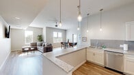 Located at 109 N Lexington St in Manor, TX, this well-appointed single-story home offers 2 bedrooms and 2 bathrooms within a thoughtfully designed open-concept floor plan. The heart of the home is a stunning kitchen featuring white shaker cabinetry, stainless steel appliances, a grey tile backsplash, and an expansive granite-topped peninsula with bar seating—all beneath soaring vaulted ceilings with elegant pendant lighting. The kitchen flows seamlessly into the dining area, which is bathed in natural light from large windows and a glass door, and the comfortable living room, which features recessed lighting and wood-look flooring throughout. A long, well-lit hallway connects the main living areas to the private quarters. Both bedrooms are bright and restful, equipped with ceiling fans and large windows that bring in natural light. The primary bedroom includes wall-mounted TV capability and generous closet space. The bathrooms are finished with neutral tile surrounds, granite vanity countertops, and white cabinetry. Clean lines, a neutral color palette, and consistent finishes create a cohesive, modern ambiance throughout the entire home.