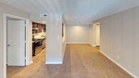 This single-floor residence offers a practical and comfortable layout designed to maximize livability. The kitchen is a standout feature, showcasing rich dark cabinetry, granite-style countertops, wood-look flooring, and a full suite of stainless steel appliances including a refrigerator, range, and over-the-range microwave. Recessed lighting adds a polished finish to the culinary space.

The open living area flows naturally from the kitchen via a pass-through counter, creating a connected and airy feel. Plush wall-to-wall carpeting runs throughout the living and bedroom spaces, adding warmth and comfort underfoot. Ceiling fans in both the living room and bedroom provide efficient climate control, while windows dressed with horizontal blinds allow for natural light and privacy.

The bedroom is generously sized and includes access to a large walk-in closet outfitted with wire shelving for organized storage. The bathroom is clean and functional, featuring wood-look tile flooring, a toilet, and a full-size soaking tub with a tub surround. Neutral gray tones and white trim throughout the space create a cohesive and understated aesthetic, offering a versatile canvas ready for personalization.