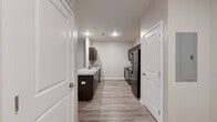 This contemporary single-floor residence is thoughtfully designed with a clean, modern aesthetic carried consistently throughout. Light wood-style luxury vinyl plank flooring flows seamlessly across every room, complemented by neutral warm-gray walls and crisp white trim and doors.

The kitchen is a standout feature, offering a galley-style layout with dark espresso cabinetry on both sides, light granite-style countertops, a double-basin sink, and a full suite of black appliances including a refrigerator, range, and built-in microwave. A peninsula with a matching countertop provides additional prep space and opens toward the living area, creating an open and connected feel.

The bedrooms are generously proportioned, each featuring ceiling fans, ample natural light, and closet access. One bedroom includes a sliding glass door leading to an outdoor area, while another offers a large window with exterior views. The bathroom is finished with light tile flooring, a bathtub with shower, and clean white fixtures. A dedicated hallway connects the bedroom and bathroom areas, providing a sense of privacy.

Throughout the space, recessed lighting and well-placed windows ensure bright, welcoming interiors. The overall ambiance is fresh, functional, and move-in ready, with a cohesive modern design from room to room.