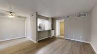 This single-floor residence offers three bedrooms, one bathroom, and a thoughtfully designed layout that maximizes every square foot. The open-concept living and kitchen area forms the heart of the home, featuring light-toned luxury vinyl plank flooring, neutral gray walls, and a textured ceiling. A large window dressed with vertical blinds fills the living room with natural light, while a front entry door provides convenient access.

The kitchen is positioned behind a half-wall pass-through, outfitted with crisp white cabinetry, quartz-style countertops, a stainless steel undermount sink with a brushed nickel faucet, and stainless steel appliances including a refrigerator and dishwasher. A pantry cabinet provides additional storage.

The bedrooms offer plush carpeting, ceiling fans, and natural light from windows with blinds. One bedroom stands out with elegant wainscoting-style wall paneling, adding a refined architectural detail. Additional bedrooms include built-in closets with bifold doors for practical storage. A hallway connects the bedrooms with two closets for added convenience.

The bathroom is clean and functional, featuring a tiled tub-shower combo, white vanity with gray countertop, and wood-look flooring. The overall design presents a cohesive, modern aesthetic with a neutral palette throughout.