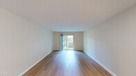 This single-floor residence offers a clean, functional layout with a thoughtful mix of materials and finishes throughout. The main living area is a standout feature, showcasing smooth hardwood flooring that reflects natural light pouring in through a large sliding glass door. This door opens to a private balcony overlooking lush greenery, creating a seamless indoor-outdoor connection and a sense of openness. The neutral, warm-toned walls complement the light wood floors, giving the living space a bright and airy quality.

The kitchen is well-equipped with white shaker-style cabinetry, brushed nickel hardware, and generous granite countertops featuring subtle speckled patterning. An undermount stainless steel sink adds a modern touch, while ample upper and lower cabinet storage ensures practicality.

The bedroom areas are finished with soft, neutral carpeting for added comfort, each offering natural light through windows with vertical blinds. Closet space is provided via bifold doors. A connecting door leads back to the hardwood-floored areas, maintaining a cohesive flow through the unit.

The bathroom is finished in crisp white tile flooring and features a full tub-shower combination with a curved curtain rod, a vanity with under-sink storage, and brushed nickel fixtures throughout. The overall aesthetic is clean, minimal, and move-in ready.