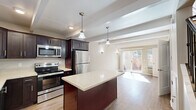 Located at 38800 Hastings St in Fremont, CA, this two-story, 2-bedroom, 1-bathroom home offers a well-organized layout spread across two floors. The main floor hosts an open-concept kitchen and living area, where rich dark-cabinetry contrasts beautifully with light quartz countertops and a central island. Stainless steel appliances — including a range, microwave, and refrigerator — are complemented by warm hardwood-style flooring and pendant lighting. The living area features exposed beam ceiling details, wall sconces, and sliding glass doors that open to a private outdoor patio, filling the space with abundant natural light. Upstairs, two carpeted bedrooms offer a comfortable retreat, each with ceiling fans, baseboard heating, and windows that bring in natural light. One bedroom includes a wall-mounted mini-split unit for added climate control. The full bathroom is finished with a dark-cabinet vanity, wood-style flooring, and a tub-shower combination. A dedicated utility room and closet provide practical storage solutions. The neutral color palette and thoughtful finishes throughout create a clean, cohesive ambiance suited for everyday living.