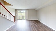 Located at 128 W Pleasant St in Manlius, NY, this three-floor home offers a well-organized layout across its levels, providing comfortable and functional living spaces throughout. The main living floor features an open-plan kitchen and living room with warm hardwood-style flooring. The kitchen is equipped with rich, warm-toned wood cabinetry, granite-look countertops, and white appliances including a gas range, refrigerator, and dishwasher, complemented by a window above the sink that brings in natural light. The living room opens to the outdoors through a sliding glass door, offering views of the surrounding greenery and access to a balcony-style railing. The upper floor houses two bedrooms, each featuring plush carpeting, neutral-toned walls, and ample closet space with built-in closet doors. The primary bedroom includes multiple doorways, providing a generous and versatile layout. Two full bathrooms serve the home, one featuring a clean white tub-shower combination with brushed nickel fixtures, and another with a modern pedestal-style sink and framed mirror. The lower level includes an unfinished utility space with painted concrete block walls, exposed framing, and ductwork — ideal for storage or mechanical use. A hallway and two staircases connect all three floors seamlessly.