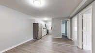 This single-floor unit presents a thoughtfully updated interior finished in soft grey tones with white trim, creating a clean and cohesive aesthetic throughout. The layout flows from a welcoming entryway — equipped with a baseboard heater and smoke detector — into the main living areas beyond.

The kitchen is well-appointed with white shaker-style cabinetry extending to the ceiling for ample storage, a classic subway tile backsplash, and a full suite of stainless steel appliances including a refrigerator, gas range, and over-the-range microwave. A single-basin sink is positioned beneath a window that draws in natural light, and grey wood-look luxury vinyl plank flooring runs throughout the kitchen and common areas.

The bedrooms feature soft wall-to-wall carpeting, light grey walls, and white six-panel doors. One bedroom benefits from dual windows overlooking greenery, along with a baseboard heating unit. Additional rooms with LVP flooring provide flexible living or dining space.

The bathroom includes a full soaking tub with a surround enclosure and continues the LVP flooring found throughout the rest of the unit. Baseboard heating is present in multiple rooms, ensuring consistent comfort. The overall ambiance is bright, modern, and move-in ready.