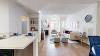 Located in the heart of Los Angeles, this well-appointed one-bedroom, two-bathroom residence offers a thoughtfully designed layout across two levels. The open-concept living area immediately impresses with vaulted ceilings, arched windows, and warm hardwood-style flooring that flows throughout. A classic fireplace serves as the focal point of the living room, complemented by generous natural light from large windows overlooking the building's landscaped courtyard below.

The modern kitchen is outfitted with rich dark wood cabinetry, stainless steel appliances including a gas range, microwave, refrigerator, and dishwasher, all anchored by a quartz peninsula with bar seating—ideal for casual dining. A dedicated dining nook features a tray ceiling and full-length mirrors, adding depth and elegance to the space.

The private bedroom is comfortably scaled, bathed in natural light through a large window, and features hardwood-style flooring. The two bathrooms include a vanity with dark wood cabinetry and a stacked in-unit washer and dryer for added convenience. The balcony offers views of the resort-style courtyard, complete with a pool and spa, providing a relaxing urban retreat.
