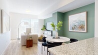 This well-designed three-story townhome in Longmont, Colorado offers a thoughtful layout spread across three levels, combining modern aesthetics with practical functionality. The entry level provides an attached garage and a flexible office space, ideal for working from home. The main living floor showcases a bright, open-concept design where the living room, dining area, and kitchen flow seamlessly together. The living room features sage green accent walls, warm hardwood-style flooring, and large sliding glass doors that fill the space with natural light. The contemporary kitchen is appointed with slate-blue cabinetry, granite countertops, a central island, stainless steel appliances, and a subway tile backsplash. A sleek half bathroom with a floating vanity and wood-look flooring completes this level. Upstairs, the two bedrooms are carpeted and bathed in natural light from large windows offering pleasant outdoor views. The primary bedroom connects directly to an en-suite bathroom featuring granite countertops and modern fixtures. A second full bathroom with granite countertops and a shower serves the additional bedroom. Throughout the home, clean white walls, recessed lighting, and ceiling fans contribute to a fresh, contemporary ambiance.