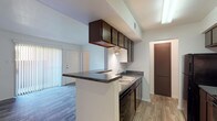 Located at 534 Hunt Lane in San Antonio, Texas, this single-floor unit offers a functional and well-organized layout throughout. The kitchen is designed as a galley-style space with dark espresso cabinetry, dark granite-style countertops, black appliances including a range, refrigerator, and dishwasher, and a double-basin sink. A peninsula counter extends into the adjacent living area, creating a natural divide while maintaining an open connection between the kitchen and living space. The living and dining area features wood-look plank flooring and is filled with natural light from a large sliding glass door that opens onto a private balcony with outdoor views. The bedroom is carpeted and generously sized, highlighted by a charming arched window that brings in natural light and a ceiling fan for year-round comfort. The bathroom includes a wide vanity with dark cabinetry and granite-style countertops, a full-size soaking tub with a tiled shower surround, and additional overhead storage. Throughout the unit, white walls and neutral finishes create a clean, bright atmosphere that is both practical and easy to personalize.