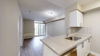 Located at 151 Beecroft Rd in North York, Toronto, this one-bedroom, one-bathroom unit offers a efficiently designed layout across a single floor. Light wood-style laminate flooring runs throughout the main living areas and bedroom, providing a cohesive and clean aesthetic.

The kitchen is a functional galley-style space featuring white cabinetry, a white tile backsplash, stainless steel appliances including a refrigerator, stove, and microwave, and a peninsula with an integrated sink that opens toward the living area. This peninsula configuration enhances the sense of openness between the kitchen and the main living space.

The bedroom is a cozy, defined room equipped with a sliding double-door closet and a window offering views of the surrounding urban skyline, allowing natural light to filter in. The neutral beige wall tones complement the light flooring throughout.

The bathroom includes a full soaker tub with an overhead shower, fully tiled surround in white, and tile flooring, presenting a clean and straightforward design. The unit also includes a balcony, providing outdoor access and additional views of the Toronto cityscape. Overall, the unit maintains a neutral, modern palette suitable for comfortable urban living.
