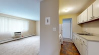 Located at 12205 Valley Lane Drive in Garfield Heights, Ohio, this 2-bedroom, 1-bathroom unit is designed for functional, comfortable living on a single floor. The layout makes efficient use of its footprint, connecting the main living area, kitchen, and bedrooms in a logical flow.

The living area features neutral beige walls, wall-to-wall carpeting, and a large window fitted with vertical blinds that allows natural light to fill the room. A wall-mounted air conditioning unit and baseboard heating provide year-round climate control.

The galley-style kitchen is equipped with white cabinetry offering ample storage, a single-basin sink, and a full-size white refrigerator and range. Stone-look tile flooring and yellow accent walls give the kitchen a distinct, warm character. A ceiling fan and entry door are also present in this area.

The generously sized primary bedroom features carpet flooring, neutral walls, a closet with bifold doors, and baseboard heating. The second bedroom is similarly appointed with carpet, a window with blinds, and baseboard heating, making it suitable as a guest room or home office.

The full bathroom includes a tub-shower combination with white tile surround, a vanity with sink, a toilet, mosaic tile flooring, and a window that provides natural ventilation and light.