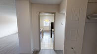 Located at 414 N Forest Park Blvd in Knoxville, Tennessee, this single-floor residence offers a practical and well-organized layout. The galley-style kitchen is equipped with stainless steel appliances, including a refrigerator and range, complemented by light wood cabinetry, ample counter space, a single-basin sink, and tile flooring. In-unit washer and dryer hookups add notable convenience. The spacious living area features durable wood-look vinyl flooring, a textured ceiling, and large windows fitted with horizontal blinds that allow generous natural light while offering views of the surrounding neighborhood. A separate carpeted room provides additional living or bedroom space, complete with a window and built-in radiator. The primary bedroom is carpeted and connects directly to a private bathroom, which features a full tub-shower combination with white tile surround and chrome fixtures. Another bedroom area offers wood-look flooring and a wall of double built-in closets with bi-fold doors, providing substantial storage. Neutral tones throughout the space create a clean, move-in-ready atmosphere well-suited for comfortable everyday living.