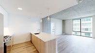 Located at 4600 N Marine Drive in Chicago's Uptown neighborhood, this two-bedroom, two-bathroom residence offers a thoughtfully designed single-floor layout with a clean, modern aesthetic. The open-concept living and kitchen area serves as the heart of the home, where a sleek kitchen island with warm wood cabinetry and a crisp white quartz countertop anchors the space. Pendant lighting hangs above the island, complementing the light wood flooring that runs throughout. Striking exposed concrete columns and ceiling sections add an industrial character that contrasts beautifully with the bright white walls.

The living area opens toward floor-to-ceiling windows, filling the space with natural light and offering views of the Chicago skyline. The bedrooms are well-proportioned, with the primary bedroom featuring large windows that frame urban views and connect to a dedicated closet with built-in wire shelving. The bathrooms are finished with wood-toned vanities, white quartz countertops, large wall mirrors, and marble-style tiled shower surrounds. A hallway connects the rooms efficiently, and a dedicated closet provides additional storage. The overall ambiance is bright, contemporary, and urban, blending industrial elements with modern finishes throughout.