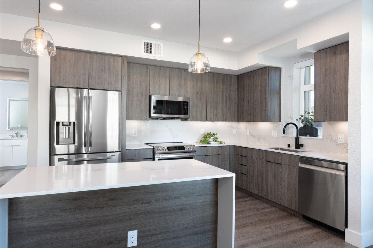 Signature Collection Kitchen with wood cabinetry, marbled quartz countertop and backsplash, upgraded stainless steel appliances, and hard surface flooring - Avalon West Dublin