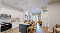 Located in Marietta, GA, this well-appointed 2-bedroom, 2-bathroom residence offers a thoughtfully designed single-level floor plan with modern finishes throughout. The open-concept kitchen and living area serves as the heart of the home, showcasing white shaker cabinetry with gold hardware, granite countertops, a striking navy center island with seating, white subway tile backsplash, and stainless steel appliances. Dual pendant lights with gold accents illuminate the island, adding a contemporary touch. The living area flows seamlessly toward French doors that open onto a private balcony, filling the space with natural light. Hardwood-style flooring runs throughout the main living areas, complementing the bright, neutral palette. The two bedrooms feature plush carpet and ample natural light, with the primary bedroom offering generous proportions and access to a well-appointed en-suite bathroom. The bathrooms are finished with marble-look tile, including a glass-enclosed walk-in shower in one and a soaking tub with floor-to-ceiling marble surround in the other. Additional conveniences include three closets, a dedicated laundry area, a utility room, and a connecting hallway that ensures a logical, functional layout throughout the home.