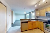 This well-appointed 2-bedroom, 2-bathroom unit at 323 N 24th St in Omaha, Nebraska offers a practical and comfortable single-floor layout. The open-concept kitchen and living area serves as the heart of the space, where light wood cabinetry, dark countertops, and a full suite of stainless steel appliances — including a refrigerator, electric range, built-in microwave, and dishwasher — create a functional cooking environment. Track lighting and pendant lights illuminate the kitchen, while the adjoining living area features neutral carpet and large windows that invite natural light. Both bedrooms are carpeted and generously sized, offering a calm, neutral palette. The primary bedroom includes a spacious walk-in closet with wire shelving, providing ample storage. A second closet is found in the additional bedroom. Each of the two bathrooms features light wood vanity cabinetry with dark countertops, large mirrors, and speckled flooring. One bathroom includes a well-lit vanity with a row of globe lights above the mirror. Throughout the unit, the clean, understated design and consistent finishes create a cohesive and move-in-ready living environment in the heart of Omaha.
