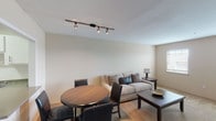 This well-appointed 2-bedroom, 2-bathroom flat is thoughtfully laid out across a single floor, offering a comfortable and functional living experience. The living room serves as the heart of the home, featuring soft carpeting, neutral wall tones, and track lighting overhead. Multiple windows allow natural light to fill the space, creating a bright and welcoming atmosphere. A dedicated dining area adjacent to the living room accommodates a round table and seating, making it ideal for everyday meals or entertaining.

The kitchen is outfitted with white cabinetry, speckled countertops, a white tile backsplash, and white appliances including a range with an overhead exhaust hood. Ample cabinet storage and open shelving provide practical functionality.

Both bedrooms are generously sized, featuring plush carpeting, neutral walls, and windows with blinds that offer natural light and privacy. The primary bedroom includes a ceiling fan with light fixture, while the secondary bedroom benefits from its own window and dresser space.

The two full bathrooms are finished with tiled surrounds, speckled countertop vanities, and large mirrors. One bathroom features a shower-only setup, while the other includes a full tub-shower combination, catering to a variety of preferences.