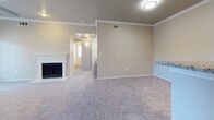 This single-floor residence offers a thoughtfully designed layout that balances comfort and functionality. The living area serves as the heart of the home, featuring a classic white-mantled fireplace, crown molding, and soft carpeting that extends throughout the main gathering spaces. The room flows naturally toward a dedicated entryway, creating a welcoming sense of arrival.

The kitchen is a standout feature, outfitted with crisp white cabinetry, granite countertops, and stainless steel appliances including a refrigerator, dishwasher, and range. Wood-look flooring anchors the kitchen, providing a clean contrast to the carpeted living areas. A breakfast bar peninsula connects the kitchen to the adjacent living and dining space, making it ideal for both everyday meals and entertaining.

The bedrooms are generously sized, each finished with plush carpet and large windows fitted with blinds that invite natural light while maintaining privacy. Ceiling fans in the bedrooms add both comfort and practicality. The neutral, warm-toned walls throughout the residence create a calm and versatile backdrop adaptable to a variety of interior styles.

Overall, the space presents a clean, move-in-ready environment with consistent finishes, practical amenities, and a cohesive design that makes efficient use of the single-level floor plan.