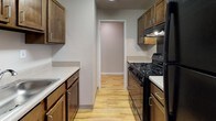 Located at 4212 E Capital St NE in Washington, DC, this single-floor residence offers a clean, move-in-ready layout with consistent warm-toned hardwood-style flooring flowing throughout every room, creating a cohesive and inviting atmosphere.

The living and common areas are open and well-proportioned, with neutral gray walls and crisp white baseboards that lend a fresh, modern feel. Natural light filters in through windows in the bedroom areas, offering views of surrounding greenery and providing a pleasant, airy quality to the space.

The galley-style kitchen is efficiently designed, featuring rich warm-toned wood cabinetry on both sides, light countertops, a black gas range with overhead ventilation, and a sink — offering ample workspace and storage within a compact, functional footprint. The kitchen connects directly to the rest of the living space through an open doorway.

The bedrooms are generously sized, with one featuring access to a dedicated walk-in closet complete with built-in shelving, providing excellent storage capacity. Additional rooms offer flexibility for use as bedrooms, a home office, or a den.

The bathroom is finished with classic blue ceramic wall tiles, a mosaic tile floor, a wood-tone vanity with mirror, and a shower enclosure, reflecting a timeless residential character. Overall, the space presents a practical and comfortable single-level layout well-suited for everyday living in the heart of Washington, DC.