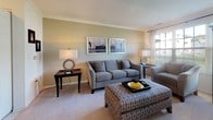 Located at 2000 Varsity Ln in Bear, Delaware, this single-floor residence offers a thoughtfully designed layout with comfortable living spaces and consistent finishes throughout. The living room is a welcoming focal point, featuring plush carpeting, crown molding, warm neutral walls, and large windows that invite generous natural light and views of the surrounding neighborhood. The space accommodates ample seating and connects seamlessly to the rest of the home. Adjacent to the living area, the dining room offers carpeted flooring, crown molding, and a sliding glass door dressed with patterned drapes, creating an elegant setting for entertaining. The galley-style kitchen is efficiently arranged with light wood cabinetry, tile flooring, laminate countertops, a breakfast bar, and standard appliances including a range, refrigerator, and dishwasher. The bedrooms are carpeted and bright, each featuring ceiling fans and windows with natural light. One bedroom showcases a ceiling fan and decorative accents, while another offers a cozy sitting nook with oversized windows. The full bathroom is clean and functional, finished with tile flooring, a vanity with ample storage, a well-lit mirror, and a shower with a decorative curtain. Throughout, the home maintains a cohesive, comfortable aesthetic suited for everyday living.