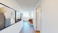 Located on the 28th floor of a high-rise building along Macleod Trail SE in downtown Calgary, this one-bedroom, one-bathroom unit delivers an efficiently designed layout with a strong emphasis on natural light and sweeping urban views. Floor-to-ceiling windows in the living area frame dramatic panoramic vistas of the Calgary skyline, flooding the space with daylight and creating a bright, airy atmosphere throughout.

The open-concept kitchen and living room function as the central hub of the unit. The kitchen features a clean, contemporary design with flat-panel white cabinetry extending to the ceiling, stainless steel appliances including a full-size refrigerator, electric range, built-in microwave, and dishwasher, complemented by a white subway tile backsplash and grey composite countertops. A compact island with seating adds functional prep and dining space.

The living area benefits directly from the expansive window wall, with hardwood-style flooring running continuously throughout the unit, reinforcing a cohesive, modern aesthetic.

The bedroom is a well-proportioned private retreat featuring a sliding door closet with built-in shelving. The four-piece bathroom is finished with large-format marble-style wall tiles surrounding the soaker tub and shower, a floating white vanity, and warm wood-tone flooring, completing the unit's polished, contemporary character.