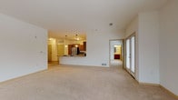 Located at 1200 N 62nd St in Wauwatosa, Wisconsin, this single-floor unit offers a well-designed, open-concept layout that seamlessly connects the living, dining, and kitchen areas. The spacious living room features plush wall-to-wall carpeting and is filled with natural light from a large sliding glass door that opens to the outdoors. A pass-through peninsula with pendant lighting bridges the living space to the kitchen, creating an inviting and functional flow.

The kitchen is outfitted with warm medium-toned wood cabinetry, granite countertops, hardwood flooring, and a full suite of stainless steel appliances, including a refrigerator, electric range, and microwave. Ample cabinet storage lines the walls, providing generous space for kitchen essentials.

The unit includes carpeted bedrooms, one of which features a large window with views of the surrounding building exterior. Two bathrooms are present: one with a walk-in shower, wood vanity, and tile flooring, and a second with an extended vanity countertop, a tub-shower combination, and tile flooring. A dedicated in-unit laundry closet houses a full-sized front-loading washer and dryer, adding everyday convenience. The overall aesthetic is clean and neutral, with consistent warm wood tones carried throughout the cabinetry and finishes.