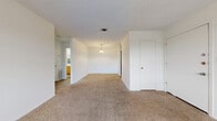Located in San Marcos, TX, this single-floor, 2-bedroom, 1-bathroom residence offers a practical and functional layout. The living area is carpeted in a warm neutral tone, with a textured ceiling overhead and a pendant light fixture that adds a subtle focal point. An entry closet near the front door provides convenient storage upon arrival. The spacious primary bedroom features dual hanging rods in its walk-in closet, carpeted flooring, and a textured ceiling, making it a generous and versatile space. The second bedroom is equally comfortable, with carpet, a ceiling fan with integrated lighting, and a large window that invites natural light. The galley-style kitchen is efficiently designed with warm wood-toned cabinetry, white countertops, and wood-look vinyl flooring. It is equipped with a black electric range, a refrigerator, and a sink. The full bathroom includes a single-sink vanity with warm wood cabinetry, a large mirror, a tub-shower combination, and wood-look vinyl flooring. Throughout the residence, white walls and neutral finishes create a clean, cohesive aesthetic, providing a versatile canvas for personalization. Central HVAC vents are present in each room, ensuring year-round comfort.