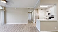 This thoughtfully designed one-bedroom, one-bathroom unit offers a comfortable and functional living experience across a single floor. The open-concept layout seamlessly connects the kitchen, dining, and living areas, creating an airy and cohesive flow throughout the space. Light wood-look flooring runs through the main living areas, complemented by warm neutral tones on the walls and crisp crown molding throughout.

The kitchen is a standout feature, showcasing white cabinetry with modern hardware, light quartz countertops, a stainless steel undermount sink, and a full suite of stainless steel appliances including a refrigerator, range, and built-in microwave. Adjacent to the kitchen, the dining area provides a natural transition into the expansive living room, which features plush carpeting, a classic white-mantled fireplace, a ceiling fan, and multiple windows that invite abundant natural light and outdoor views.

The generously sized bedroom includes carpeted flooring, a ceiling fan, a large window, and access to a sliding glass door. The full bathroom is well-appointed with white cabinetry, quartz countertops, a tub-shower combination with tile surround, and wood-look flooring. A walk-in closet with wire shelving provides ample storage. A hallway connects the private areas of the unit efficiently.