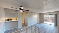 This thoughtfully designed single-floor, one-bedroom, one-bathroom unit offers an efficient and comfortable layout across a compact but functional footprint. Throughout the space, light-toned vinyl plank flooring creates a cohesive and modern aesthetic, complemented by neutral beige walls and textured popcorn ceilings.

The open living area is bright and airy, centered around a ceiling fan with an integrated light fixture. A sliding glass door floods the room with natural light and provides direct access to a fenced outdoor patio, offering pleasant outdoor views. The kitchen features a galley-style configuration with dark cabinetry, light countertops, a stainless steel double sink, a dishwasher, and black appliances including a refrigerator and range. A pass-through counter connects the kitchen to the living area, enhancing the open feel.

The bedroom is a well-sized, quiet retreat with its own ceiling fan, a natural light window with blinds, and access to two closets providing ample storage. The full bathroom is cleanly appointed with a tub-shower combination, a vanity featuring dark cabinetry with a light countertop, a large mirror, and matching vinyl plank flooring. Floor vents throughout the unit ensure consistent climate control, rounding out a practical and move-in-ready living space.
