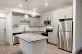 Located at 3210 Champion Ring Rd in Fort Myers, FL, this well-appointed 2-bedroom, 1-bathroom unit offers a thoughtfully designed single-level layout with modern finishes throughout. The open-concept kitchen is a standout, featuring sleek gray cabinetry, granite countertops, a decorative tile backsplash, stainless steel appliances including a refrigerator, range, microwave, and dishwasher, and a central island with pendant lighting overhead — ideal for cooking and entertaining. Wood-look flooring flows seamlessly throughout the unit, lending a warm, cohesive aesthetic. The spacious primary bedroom includes vaulted ceilings, a ceiling fan, and French doors that invite natural light and outdoor views. The second bedroom also features a ceiling fan and a large window with natural light. A connecting hallway provides access to a dedicated closet, offering convenient storage. The full bathroom is finished with a granite-topped vanity, wood-look tile flooring, and a glass-enclosed walk-in shower with marble-style tile surround. Clean white walls and an abundance of natural light contribute to a bright, airy ambiance throughout the entire space, creating a comfortable and stylish living environment.