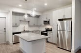 Located at 3210 Champion Ring Rd in Fort Myers, FL, this well-appointed 2-bedroom, 1-bathroom unit offers a thoughtfully designed single-level layout with modern finishes throughout. The open-concept kitchen is a standout, featuring sleek gray cabinetry, granite countertops, a decorative tile backsplash, stainless steel appliances including a refrigerator, range, microwave, and dishwasher, and a central island with pendant lighting overhead — ideal for cooking and entertaining. Wood-look flooring flows seamlessly throughout the unit, lending a warm, cohesive aesthetic. The spacious primary bedroom includes vaulted ceilings, a ceiling fan, and French doors that invite natural light and outdoor views. The second bedroom also features a ceiling fan and a large window with natural light. A connecting hallway provides access to a dedicated closet, offering convenient storage. The full bathroom is finished with a granite-topped vanity, wood-look tile flooring, and a glass-enclosed walk-in shower with marble-style tile surround. Clean white walls and an abundance of natural light contribute to a bright, airy ambiance throughout the entire space, creating a comfortable and stylish living environment.