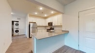 Located at 34 Bank St in Netcong, NJ, this single-floor residence offers a thoughtfully designed open-concept layout with modern finishes throughout. The living area features smooth wood-look flooring that extends seamlessly toward the kitchen, creating a bright and cohesive common space with a clean, contemporary feel.

The kitchen is a standout feature, outfitted with crisp white shaker cabinetry, grey quartz-style countertops, and a full suite of stainless steel appliances including a refrigerator, gas range, and over-the-range microwave. A peninsula with an integrated sink and breakfast bar adds both functionality and a natural division between the kitchen and living area. Recessed lighting overhead enhances the bright, welcoming atmosphere.

The bedroom features plush carpeting, generous wall space, and a walk-in closet with built-in rod storage. A large window admits abundant natural light with views of surrounding greenery, contributing to a calm and airy ambiance.

The bathroom is finished with marble-style tile surrounding the full soaking tub and shower, complemented by a vanity with grey countertops, white cabinetry, and light tile flooring, resulting in a clean and polished aesthetic throughout.