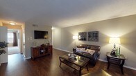 Located at 1601 Hill Crest Rd in Mobile, Alabama, this single-floor home offers a well-designed layout with a cohesive, neutral color palette and warm finishes throughout. The spacious living room is a standout feature, showcasing rich dark hardwood-style flooring, a textured ceiling, and a wood-burning fireplace flanked by built-in shelving — creating an inviting focal point for the room. A glass-top coffee table and ample seating area complete the comfortable atmosphere, while a glass-paneled exterior door allows natural light to filter in.

The dining area sits adjacent to the living space and benefits from a large window overlooking an outdoor deck, filling the room with natural light. The kitchen is outfitted with dark espresso cabinetry, granite-style countertops, a mosaic tile backsplash, and black appliances including a refrigerator, stove, and dishwasher, all set over matching hardwood-style flooring.

The primary bedroom is generously sized with plush carpeting, a ceiling fan, and direct access to both a walk-in closet and a private en-suite bathroom. The bathroom features dark wood cabinetry, a granite-style vanity top, and hardwood-style flooring. A second bedroom with carpeting and a ceiling fan is also present. The home's consistent finishes and functional layout make it a practical and attractive residence.