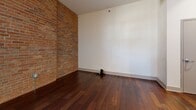 Located at 427 N Pershing Ave in Davenport, Iowa, this 2-bedroom, 1-bathroom loft-style unit masterfully combines industrial heritage with contemporary living. Rich hardwood flooring flows throughout the open living areas, anchored by striking original timber post columns that serve as architectural focal points. Exposed brick walls add warmth and texture, lending the space an authentic, urban character.

The combined kitchen and living area is generously proportioned, featuring soaring ceilings with exposed ductwork and track lighting. The well-appointed kitchen includes rich wood cabinetry, granite countertops, stainless steel appliances, and a large peninsula island—ideal for both cooking and casual dining.

The two bedrooms continue the loft aesthetic, with hardwood floors, timber columns, and high ceilings. One bedroom features a charming sliding barn door, while another opens to exposed brick walls and natural light from well-placed windows. A dedicated closet provides additional storage.

The bathroom is finished with clean tile flooring and a tiled tub-shower surround. A standout convenience is the in-unit stacked Whirlpool washer and dryer, neatly integrated into the layout. This thoughtfully designed unit delivers a compelling blend of historic industrial character and modern comfort.