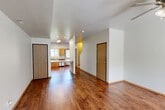 Located at 1103 West Broadway in Columbia, Missouri, this two-story, two-bedroom, two-bathroom home offers a practical and well-organized layout spread across two evenly sized floors. The main level features an open-concept living area that flows seamlessly into the kitchen, which is equipped with stainless steel appliances including a refrigerator with ice maker, electric range, microwave, and dishwasher. Warm-toned wood cabinetry lines the kitchen walls, complemented by a peninsula counter that separates the cooking area from the living space. Rich hardwood-style flooring runs throughout both levels, adding warmth and continuity to the interior. A textured ceiling and crisp white walls define the main floor's clean aesthetic. Upstairs, both bedrooms are generously sized, each featuring ceiling fans with light fixtures, windows that bring in natural light with views of surrounding greenery, and the same hardwood-style flooring. The primary bedroom offers a notably spacious footprint. Both bathrooms are fitted with full tub-shower combinations in white surrounds with chrome fixtures. Additional spaces include closets, a utility room, a hallway, and two staircases connecting the floors, providing efficient circulation throughout the home.