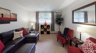 Located at 12 Heritage Ln in Leominster, MA, this single-floor unit offers a practical and comfortable layout designed to maximize everyday living. The living room serves as the central gathering space, featuring carpet flooring, a large window that brings in natural light, and room for both seating and a dedicated workspace. A wall-mounted air conditioning unit provides climate control, while baseboard heating is present throughout the unit.

The dining area is situated adjacent to the living space, providing a defined area for meals with enough room for a modest dining set. The kitchen features warm wood cabinetry extending to the upper walls for ample storage, light countertops, tile flooring, and white appliances including a range and dishwasher, keeping the space clean and functional.

The bedroom is a calm retreat with carpet flooring, windows dressed with sheer curtains that allow soft natural light, and a closet with a standard hanging rod. The full bathroom includes a vanity with wood cabinetry, a white countertop, tile flooring, and a tub-shower combination. Neutral tones throughout the unit create a cohesive and easy-to-personalize atmosphere.