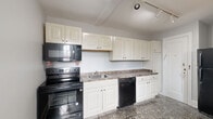 Located at 703 W Ferry St in Buffalo, NY, this single-floor, two-bedroom unit offers a well-organized layout spanning a comfortable footprint. The interior is characterized by warm, polished hardwood floors that extend throughout the living areas and bedrooms, complemented by soft gray-toned walls that create a calm, neutral ambiance.

The two living rooms provide versatile spaces for both relaxing and entertaining, with multiple windows allowing natural light to flow freely and offering views of the surrounding neighborhood. Classic cast-iron radiators in several rooms speak to the building's character while ensuring efficient heating.

The two bedrooms are well-proportioned, with the primary bedroom offering generous space. Each bedroom features hardwood flooring, large windows with neighborhood views, and clean, bright walls.

The kitchen is equipped with white cabinetry — both upper and lower — providing ample storage, paired with dark granite-style countertops and black appliances including a range, microwave, dishwasher, and refrigerator. Track lighting and a patterned tile floor complete the kitchen's functional design. Three hallways connect the spaces efficiently, contributing to a logical and easy-to-navigate floor plan throughout the unit.