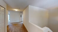 This single-floor residential unit offers a practical and comfortable layout designed for everyday living. The generously sized living room is finished with plush carpeting and features a sliding glass door that opens to a private outdoor balcony, filling the space with natural light. A pass-through window connects the living area to the kitchen, creating an open, communicative feel between spaces. The galley-style kitchen is well-equipped with white cabinetry, laminate countertops, a double-basin stainless steel sink, a full suite of white appliances including a refrigerator, electric range, built-in microwave, and dishwasher, all set atop easy-to-maintain tile flooring with track lighting overhead. A dedicated laundry room houses a full-size washer and dryer with overhead wire shelving for additional storage. The unit includes two bedrooms, each carpeted and filled with natural light from large windows. Two bathrooms serve the unit — one features a vanity with a wide mirror and Hollywood-style lighting, while the other offers a full tub-and-shower combination with tile flooring. A carpeted hallway with a built-in display niche connects the rooms, completing this thoughtfully designed home.