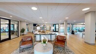 Located at 100 Mia Rose Way in Dardenne Prairie, Missouri, this thoughtfully designed amenity floor offers residents a comprehensive suite of recreational and social spaces. The centerpiece of the outdoor area is a large resort-style swimming pool surrounded by an expansive paver courtyard, complete with lounge chairs, sun beds, and seating clusters. The multi-story building's striking exterior combines contrasting red, gray, and white siding with private balconies that overlook the courtyard, creating a vibrant, community-focused atmosphere.

Inside, the bright and open lobby features light hardwood flooring, clean white columns, and abundant natural light streaming through large glass entry doors. Adjacent to the lobby is a versatile social lounge with hardwood floors, a pool table, a large wall-mounted TV, built-in shelving, a fireplace, and comfortable seating — ideal for both casual gatherings and group activities.

The fitness center is a standout feature, offering a comprehensive exercise room equipped with cardio machines including treadmills, ellipticals, and a stair climber, as well as strength training equipment, free weights, and a turf workout zone. Glass partition walls connect the fitness area to the lounge, promoting an open, integrated layout. A water station and ample floor space ensure a functional and comfortable workout environment throughout.