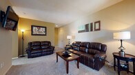 This single-floor, two-bedroom, one-bathroom residence offers a thoughtfully laid-out floor plan designed for comfortable everyday living. The spacious living room serves as the heart of the home, featuring soft carpeting, neutral-toned walls with warm accent colors, and ample room for generous seating arrangements. A dedicated dining area adjoins the living space, bathed in natural light from a large window and offering a cozy setting for meals. The kitchen is equipped with light wood cabinetry, laminate countertops, a full electric range with overhead ventilation, and durable hardwood-style flooring, providing a clean and functional cooking environment. Both bedrooms are carpeted and well-sized, each featuring windows that bring in natural light. The primary bedroom benefits from direct access to the full bathroom, which includes an extended double-vanity countertop with dual sinks, a tiled shower, and hardwood-style flooring — providing an efficient and practical layout. A dedicated in-unit laundry area houses a full-sized washer and dryer, adding significant everyday convenience. Throughout the home, the warm color palette, carpet flooring in living areas, and consistent neutral tones create a cohesive and inviting atmosphere suitable for a variety of lifestyles.