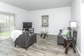 This single-floor residence at 34835 Utica Rd in Fraser, Michigan, offers a thoughtfully designed layout with a clean, contemporary aesthetic throughout. Wood-look luxury vinyl flooring runs through the main living areas, providing a cohesive and low-maintenance foundation for the space.

The open living and dining area is bright and welcoming, with a large sliding glass door dressed in vertical blinds that allows generous natural light and provides direct access to an outdoor view. The dining area features a modern chandelier overhead, a large framed mirror, and ample room for a full dining set. The living room flows naturally from this space, offering a relaxed, functional layout.

The kitchen is equipped with stainless steel appliances, including a refrigerator, range, and over-the-range microwave, complemented by white shaker-style cabinetry, light granite-style countertops, and wood-look flooring that ties in with the rest of the home.

Both bedrooms are carpeted for comfort and receive natural light through well-placed windows. One bedroom includes a walk-in closet, adding practical storage. The bathroom is finished with a granite-topped vanity, white cabinetry with brushed hardware, a tub-shower combination, and wood-look flooring, rounding out this well-maintained home.