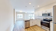 This single-story residence in Clarksville, Indiana offers a well-designed, open-concept floor plan accommodating three bedrooms and two full bathrooms. The interior is finished with light-toned luxury vinyl plank flooring throughout the main living areas, while the bedrooms feature plush carpeting for added comfort.

The kitchen serves as a central hub of the home, featuring white shaker-style cabinetry, granite countertops, and a classic white subway tile backsplash. A peninsula with an integrated sink provides additional prep space and casual seating potential. Stainless steel appliances, including a range, over-the-range microwave, dishwasher, and refrigerator, complete the kitchen. Pendant lighting accents the peninsula, adding a modern touch.

The living area is generously proportioned, with large windows and a sliding glass door allowing abundant natural light and outdoor views. Neutral gray walls create a clean, versatile backdrop throughout.

The primary bathroom features a dark-wood vanity with granite countertops, a separate walk-in shower, and hardwood-style flooring. The secondary bathroom includes a full tub and shower combination. Bedrooms are carpeted and receive natural light through standard windows, offering comfortable, quiet retreats within the home.