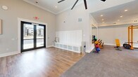 Located in Pensacola, FL, this fitness center offers a thoughtfully designed exercise space spread across a single floor. The layout is divided into distinct training zones, each tailored to a different style of workout, creating a comprehensive and functional environment for residents.

The cardio zone features multiple treadmills equipped with interactive digital displays, an elliptical, and stationary bikes, all positioned to take advantage of large sliding windows that frame views of an outdoor pool and pergola. Natural light floods the space, enhancing the open and airy atmosphere.

A dedicated strength training area houses a power rack with adjustable benches and free weights, set against large windows that bring in additional natural light and outdoor scenery. The functional training zone includes medicine ball storage, battle ropes, and open floor space, supported by durable flooring ideal for dynamic movement.

Throughout the facility, elevated ceilings adorned with crown molding add a polished architectural touch, while ceiling fans in each zone ensure consistent air circulation. Recessed lighting complements the abundant natural light. The entry area features wood-look flooring that transitions seamlessly into rubber and concrete sport flooring across the workout zones, balancing aesthetics with performance. The overall ambiance is bright, clean, and motivating.